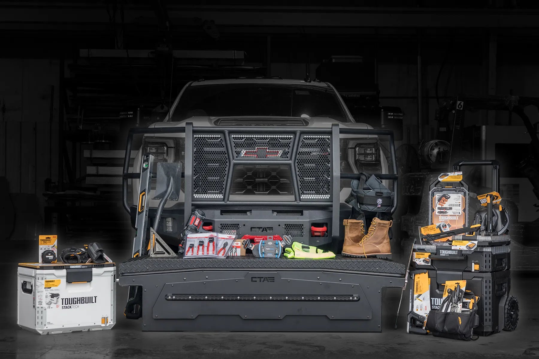 Truck in a garage with a front bumper with various tools sitting on top of a truck toolbox including toughbuilt, knipex, rollercamp, boots, and more.